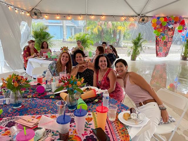 Friends laughing together around a long table under the tent